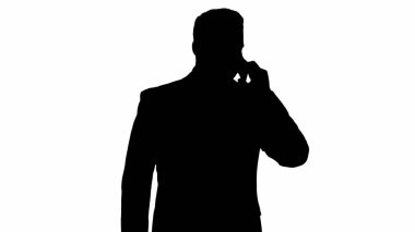 Siluet yürüyen iş adamı cep telefonuyla konuşuyor..