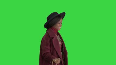 Gülümseyen Afrikalı Amerikalı moda kızı ve siyah şapkalı Yeşil Ekran, Chroma Key 'de alışveriş torbalarıyla poz veriyor..