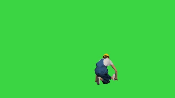 年轻的建筑工人戴着黄色的硬礼帽，手舞足蹈，最后在一个绿色屏幕上对着摄像机笑，铬钥匙. — 图库视频影像
