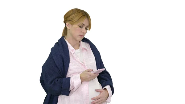 可愛いです妊娠中の女性使用彼女のスマートフォンタッチ彼女の腹st — ストック写真