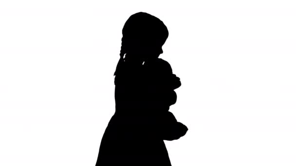 Силует Маленька дівчинка в точковій сукні Полка обіймає великого плюшевого ведмедя під час ходьби і дивлячись на камеру . — стокове відео