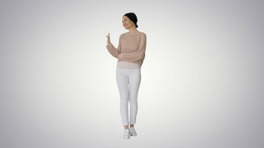 Gülümseyen genç bir kadın selamlaşmak için elini sallıyor.