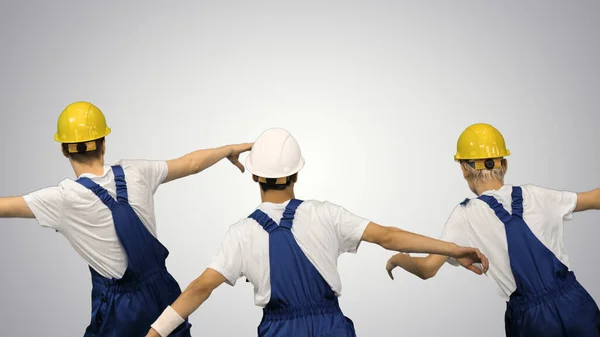 Drie mannelijke bouwvakkers in harde hoeden synchroon dansen met — Stockfoto