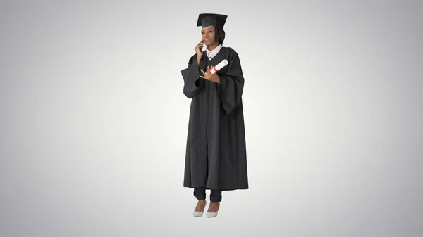 Afro-americano feminino estudante no graduação robe falando no th — Fotografia de Stock