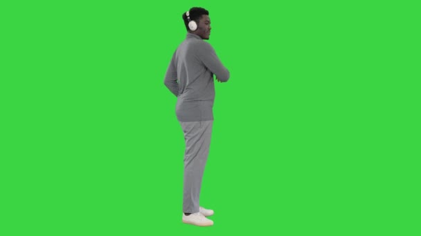 Szenvedélyes afro-amerikai férfi hallgatja a zenét a fejhallgató és a tánc a zöld képernyőn, Chroma Key. — Stock videók