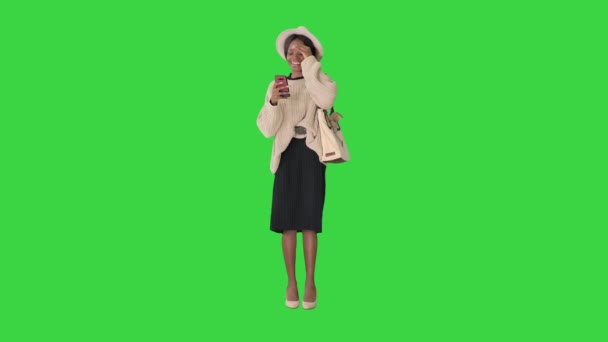 Mulher americana muito africana em camisola de malha e chapéu branco respondendo seu telefone em uma tela verde, Chroma Key. — Vídeo de Stock