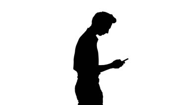 Siluetli adam cep telefonuyla yürüyor..