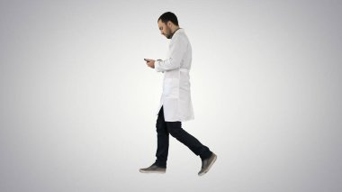 Erkek doktor gradyan arka grubunda yürüyor ve cep telefonu kullanıyor