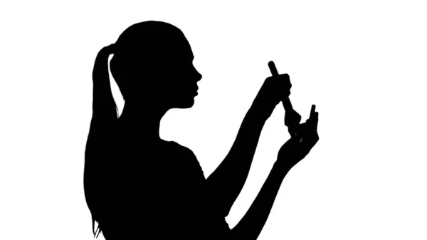 Silueta Joven hermosa mujer aplicando polvo en la mejilla con b — Foto de Stock