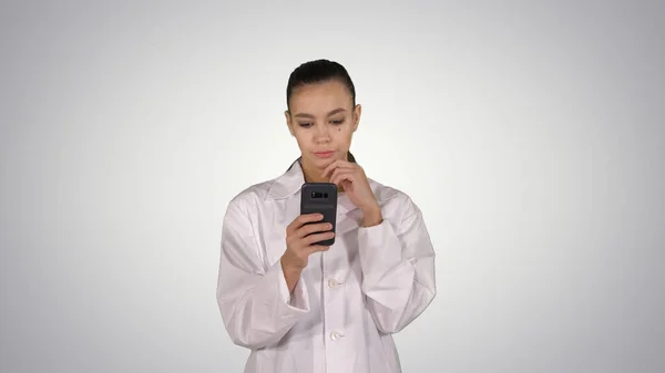 Vrolijke leuke jonge vrouw arts typen tekst op de telefoon tijdens het lopen — Stockfoto