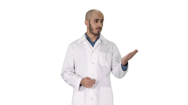 Arabo medico uomo in cappotto medico parlando e presentando con mano qualcosa su sfondo bianco. — Foto Stock