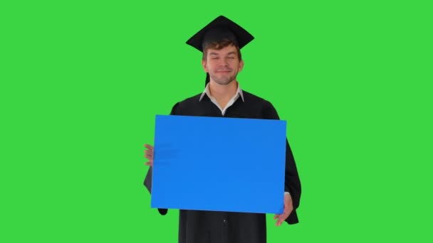 Hombre graduado sonriente en mortero sosteniendo un cartel en blanco en una pantalla verde, Chroma Key. — Vídeos de Stock