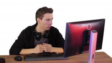 Ciddi oyuncu bilgisayar başında oturup beyaz arkaplanda maç izliyor.