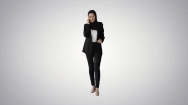 Çekici, modern Müslüman kadın gradyan arka planda cep telefonuyla yürüyor ve konuşuyor..