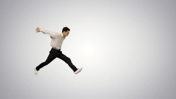Young man dressed in white shirt and black pants dancing break-dance and smiling at camera at the end on gradient background. — Stock Video