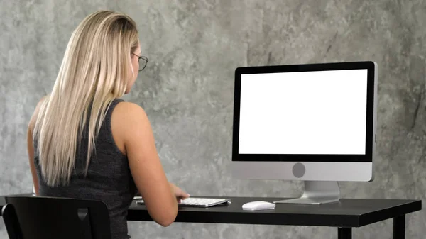 Hipster chica en gafas de moda se sienta a la mesa delante de la computación — Foto de Stock