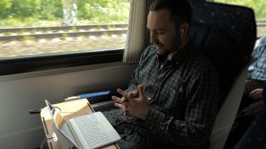 Trende laptopuyla sohbet eden bir adam..