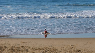 San Sebastian, İspanya - 30 Aralık 2017: Kumlu bir plajda ezici dalgalarla oynayan çocuk.