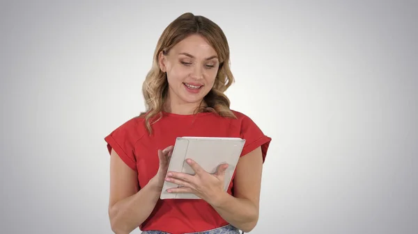 Blonde woman in red holding tablet and reading to camera from it — Stock Photo, Image