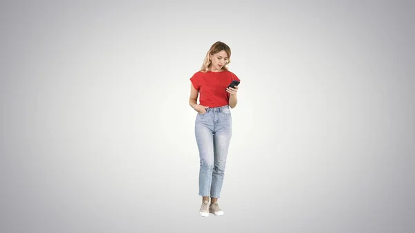 Блондинка смс зі своїм смартфоном ходить на градієнті ба — стокове фото