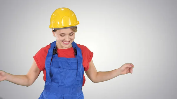 Vrouw in de bouw helm dansen op gradiënt achtergrond. — Stockfoto