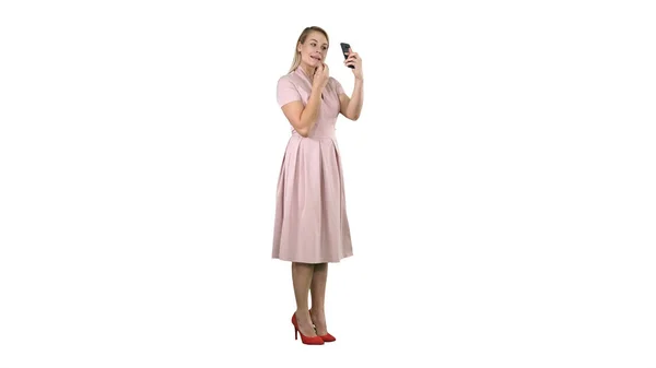 Vrouw toepassen van lippenstift kijken naar haar telefoon op een witte achtergrond — Stockfoto