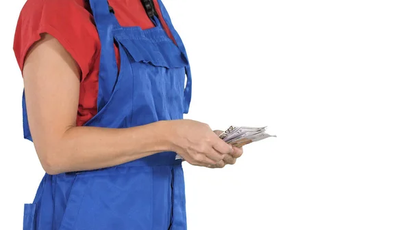 Een vrouw in een arbeiderskleren telt geld op witte achtergrond. — Stockfoto