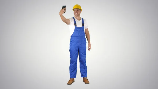 Lachende knappe jonge bouwer maken selfie met mobiele telefoon o — Stockfoto