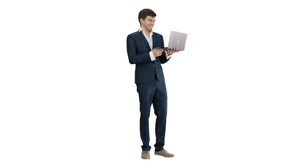 Улыбающийся молодой бизнесмен, использующий ноутбук, стоя на белом — стоковое фото