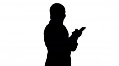 Siluet Müslüman kız tesettüre girdi ve sesli mesaj göndermek için akıllı telefon kullanıyor..