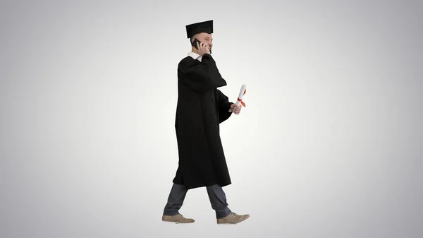 Graduating student walking and making a call on gradient backgro — Stock Photo, Image