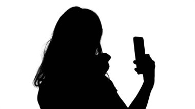 Siluet sarışın kadın telefona ruj sürüyor..