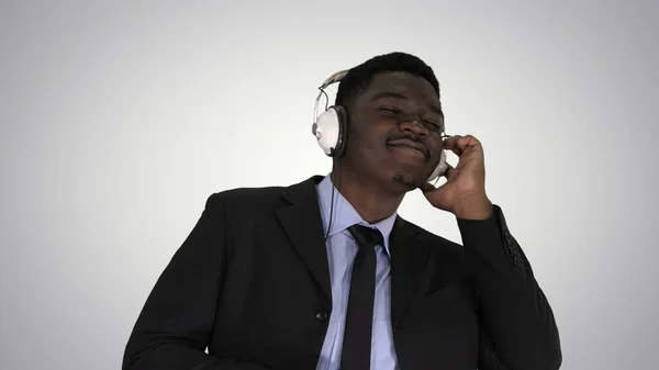 Hombre de negocios negro bailando con música en auriculares en gradiente bac —  Fotos de Stock