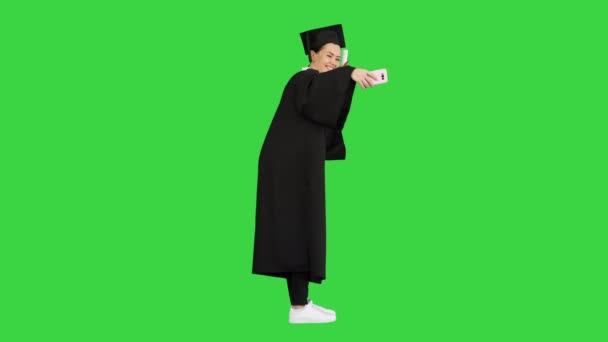 Glückliche Absolventin mit Diplom und Selfie auf ihrem Handy auf einem Green Screen, Chroma Key. — Stockvideo