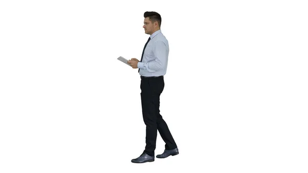 Elegante joven empresario usando tableta mientras camina sobre fondo blanco. —  Fotos de Stock