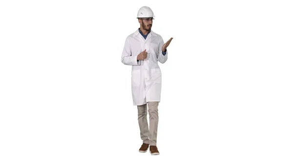 Scientist in white robe and helmet presenting pointing to side with hand and explaining to camera on white background. — Stock Photo, Image