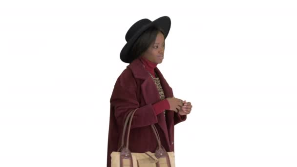 Afrykański amerykański moda dziewczyna w płaszcz i czarny kapelusz pozowanie z torebką na białym tle. — Wideo stockowe