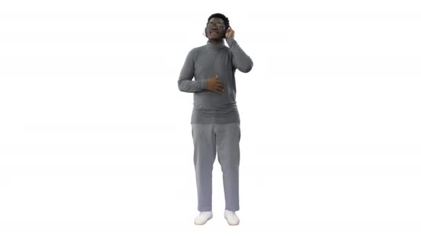 Mosolygó afro-amerikai férfi fülhallgató és mozog a zenei ritmus fehér háttér. — Stock videók
