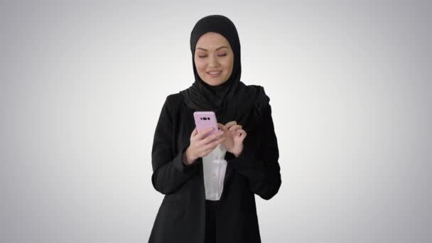 Mujer árabe sonriente usando teléfono inteligente sobre fondo de gradiente. — Vídeos de Stock