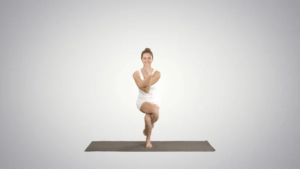 Atractiva chica de pie en la pose de equilibrio de yoga Garudasana Y —  Fotos de Stock