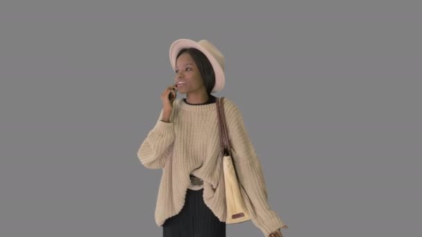 Hüsrana uğramış Afro-Amerikan kadın örgü kazak ve beyaz şapkalı telefonuyla konuşuyor, Alpha Channel. — Stok video