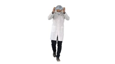Beyaz arka planda maske ve şapka takan yürüyen yakışıklı bir doktor.