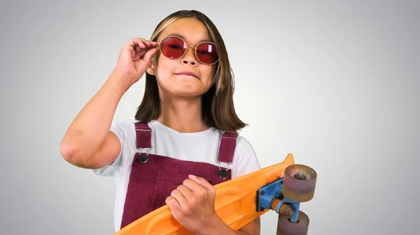 Молода азіатська школярка в відтінках зі скейтбордом в її руках — стокове фото