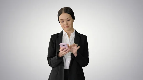 Casual hembra en un traje mensajes de texto en su teléfono en gradiente backgro —  Fotos de Stock