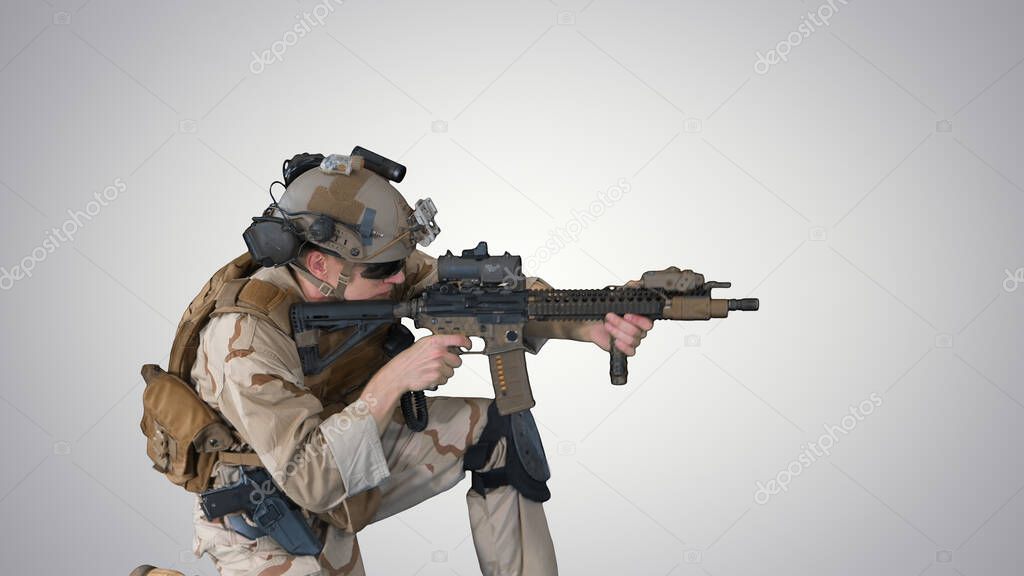 Paratrooper in uniform shooting from sitting position on gradien