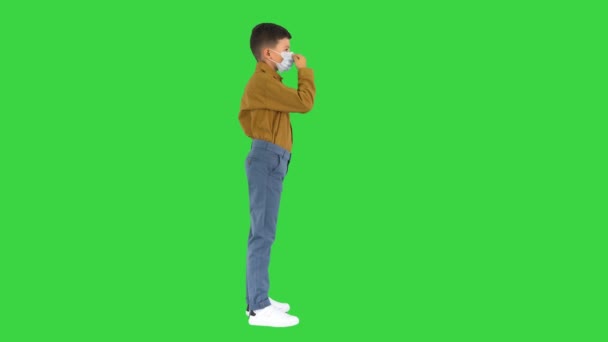 Petit garçon ajustant son masque en regardant la caméra sur un écran vert, Chroma Key. — Video