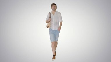 Beyaz tişörtlü yakışıklı adam çantasıyla yürüyor.