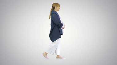 Mutlu, hamile, sarışın kadın, değişken arka planda yürüyor..