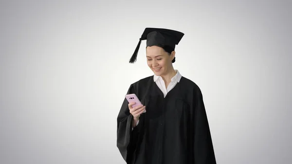 Sorridente laureata donna in mortai sms sul suo telefono whil — Foto Stock