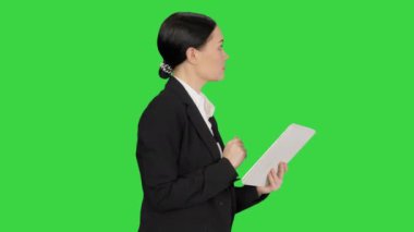 İş kadını yeşil ekranda yürürken tablet kullanıyor, Chroma Key.